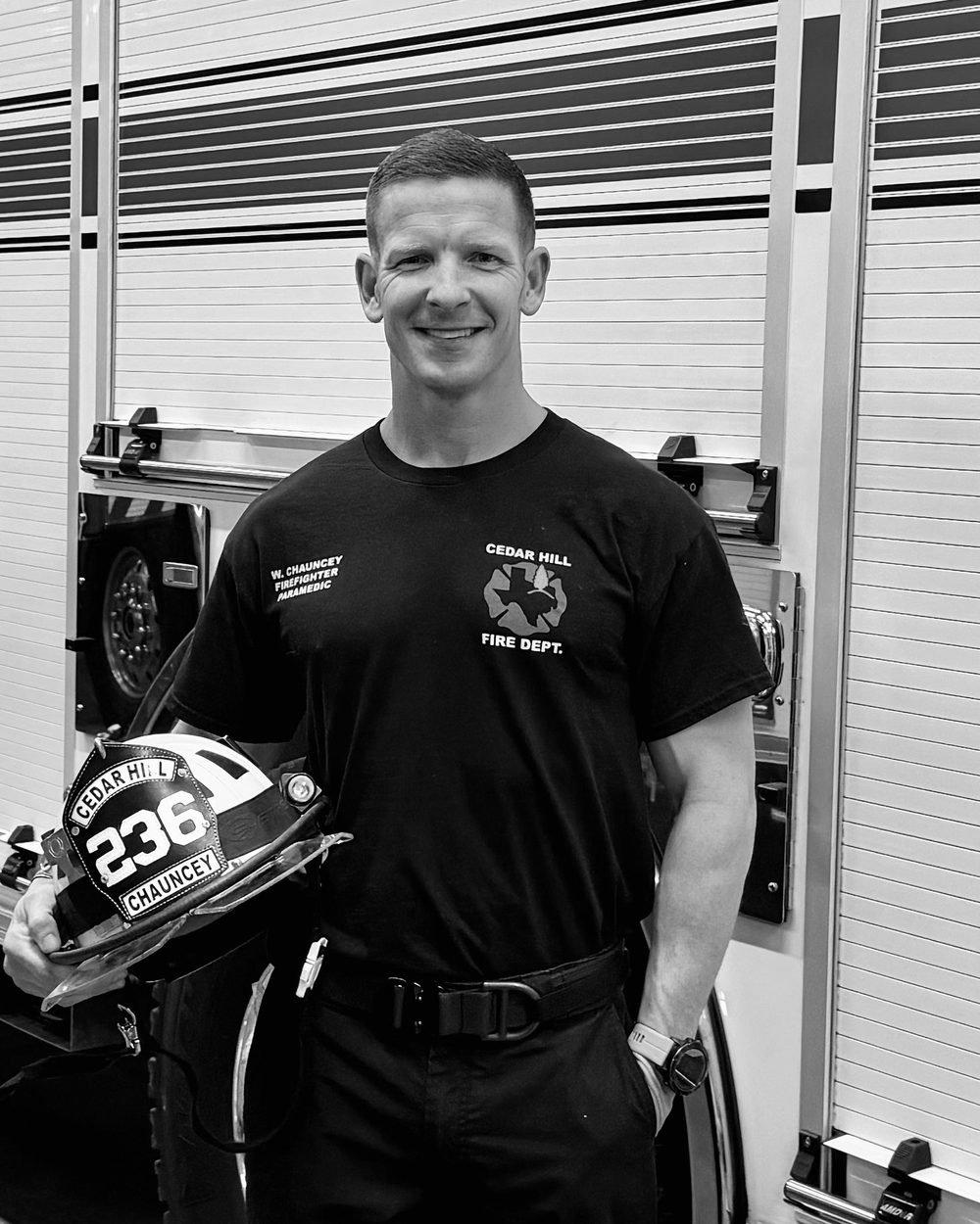 William Chauncey in uniform beside a fire engine, holding his helmet